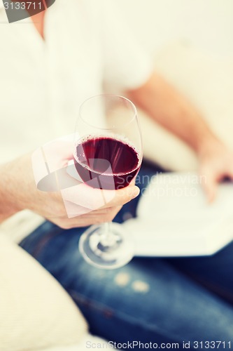 Image of male hand holdind book and glass of red wine