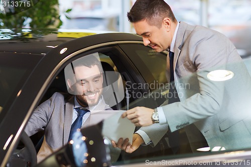 Image of happy man with car dealer in auto show or salon