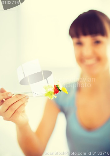 Image of woman hand holding fork with vegetables