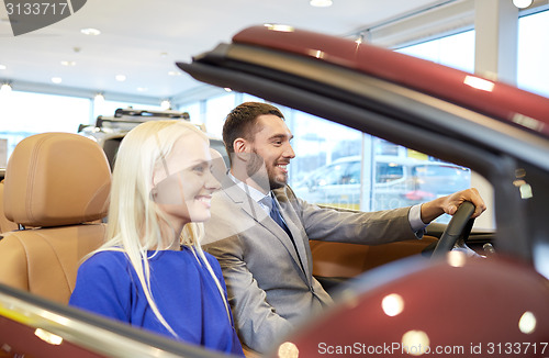 Image of happy couple sitting in car at auto show or salon