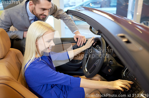 Image of happy couple buying car in auto show or salon