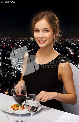 Image of smiling young woman eating main course