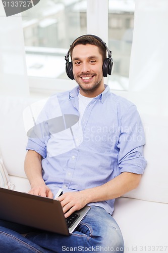 Image of smiling man with laptop and headphones at home