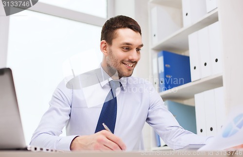 Image of businessman with laptop and papers in office