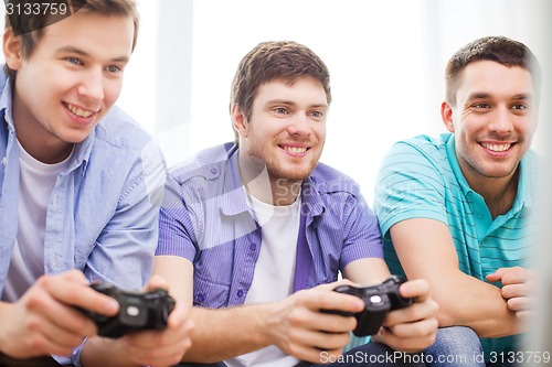 Image of smiling friends playing video games at home