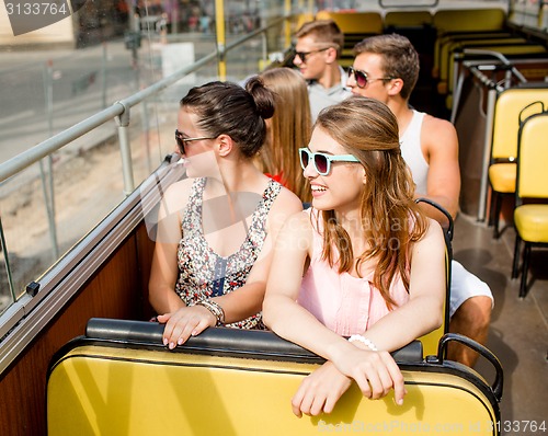 Image of group of smiling friends traveling by tour bus