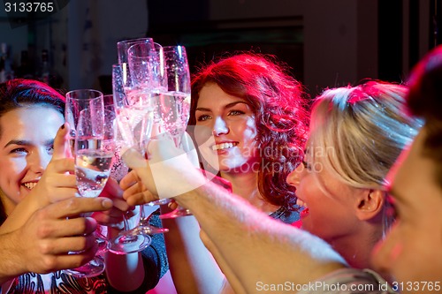 Image of smiling friends with glasses of champagne in club