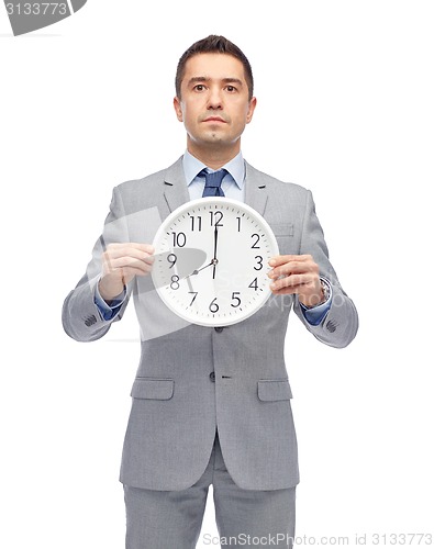 Image of businessman in suit holding clock with 8 o'clock