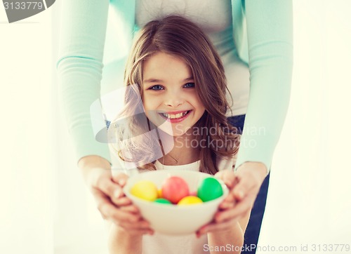 Image of smiling girl and mother holding colored eggs