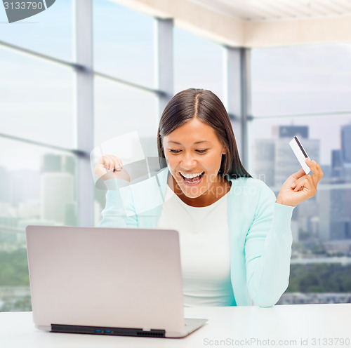 Image of happy businesswoman with laptop and credit card