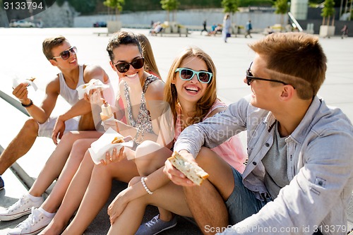 Image of group of smiling friends sitting on city square