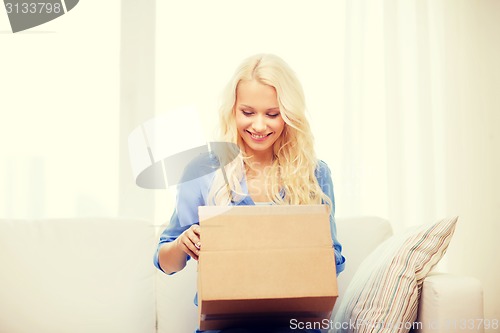 Image of smiling young woman opening cardboard box