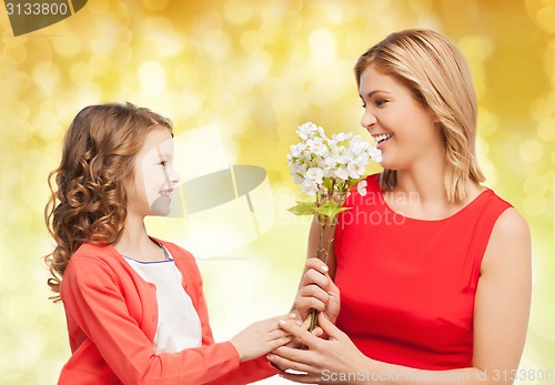Image of happy little daughter giving flowers to her mother