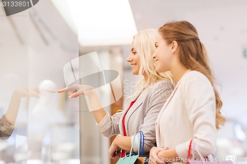 Image of happy young women with shopping bags in mall