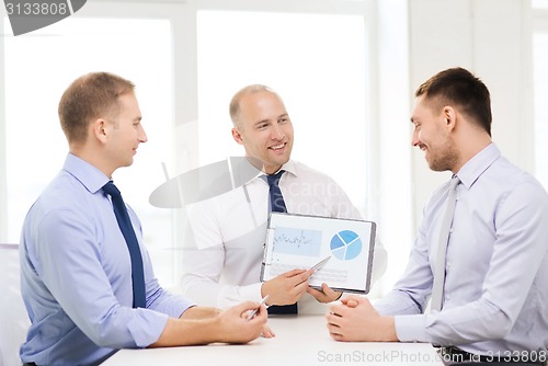 Image of smiling businessmen with papers in office