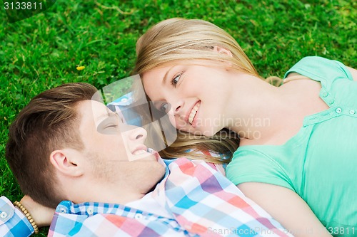 Image of smiling couple lying on grass in park