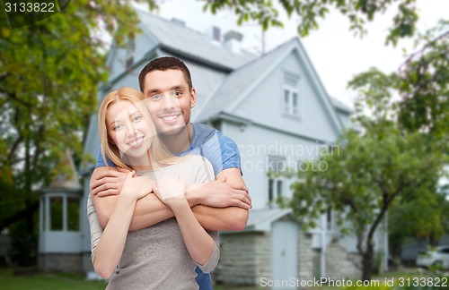 Image of smiling couple hugging over house background