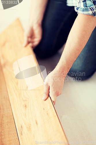 Image of close up of male hands intalling wood flooring