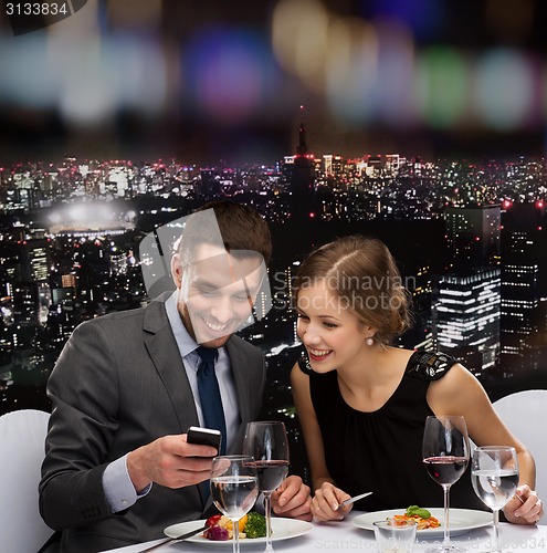 Image of smiling couple eating main course at restaurant