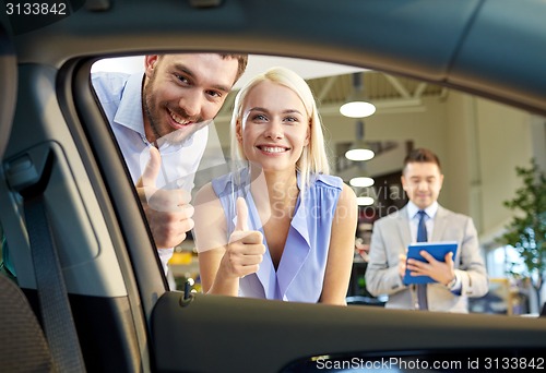 Image of happy couple with car dealer in auto show or salon