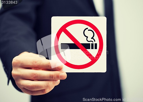 Image of man in suit holding no smoking sign