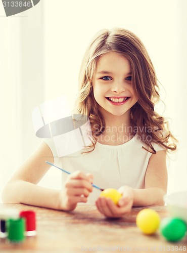 Image of smiling little girl coloring eggs for easter