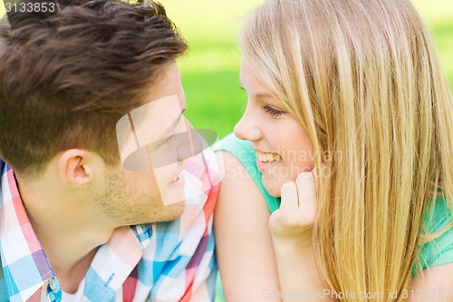 Image of smiling couple looking at each other in park