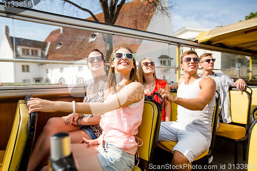 Image of group of smiling friends traveling by tour bus