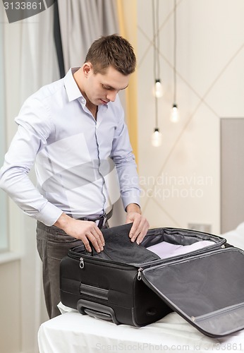 Image of businessman packing things in suitcase