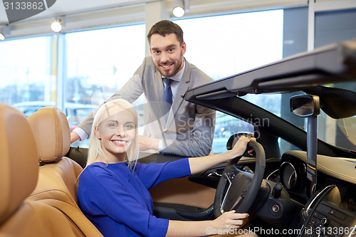 Image of happy couple buying car in auto show or salon