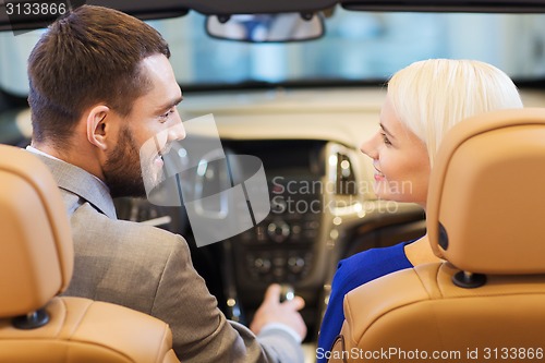 Image of happy couple sitting in car at auto show or salon