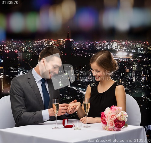 Image of man proposing to his girlfriend at restaurant