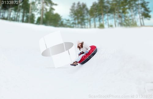 Image of happy teenage girl sliding down on snow tube