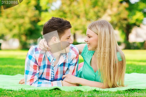 Image of smiling couple lying on blanket in park
