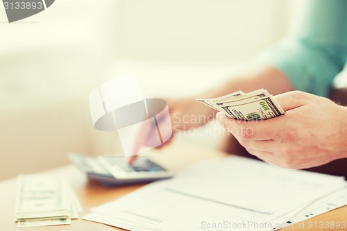 Image of close up of man counting money and making notes