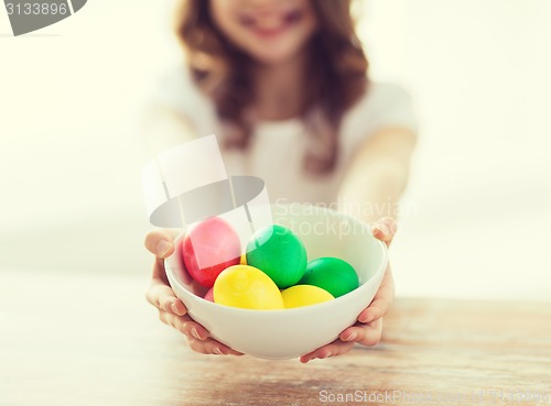 Image of close up of girl holding bowl with colored eggs