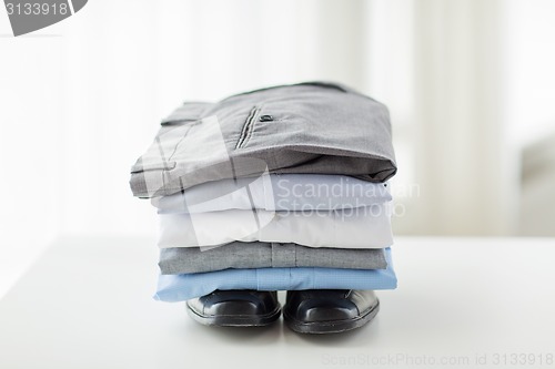 Image of close up of male shirts, pants and shoes on table