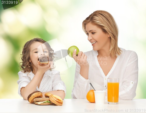 Image of happy mother and daughter eating breakfast