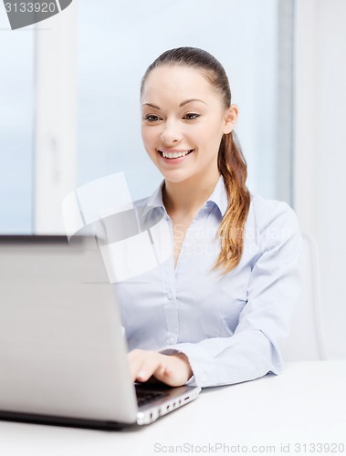 Image of smiling businesswoman with laptop in office