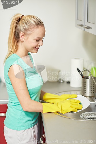 Image of happy woman washing dishes at home kitchen