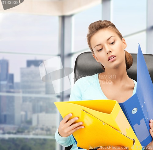 Image of young businesswoman with folders sitting in chair