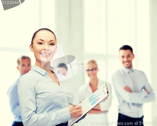 Image of young smiling businesswoman with clipboard and pen