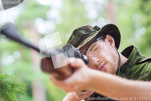 Image of young soldier or hunter with gun in forest