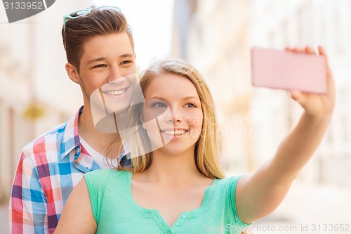 Image of smiling couple with smartphone in city