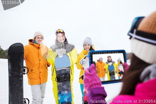 Image of happy friends with snowboards and tablet pc