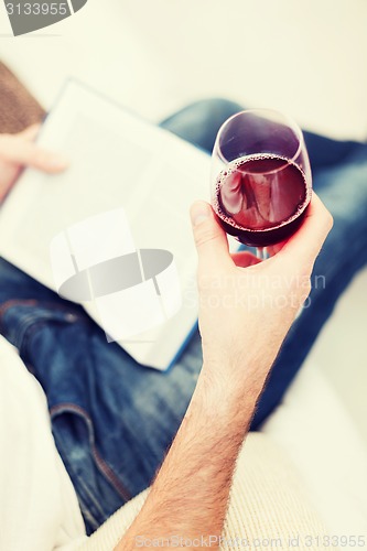 Image of male hand holdind book and glass of red wine