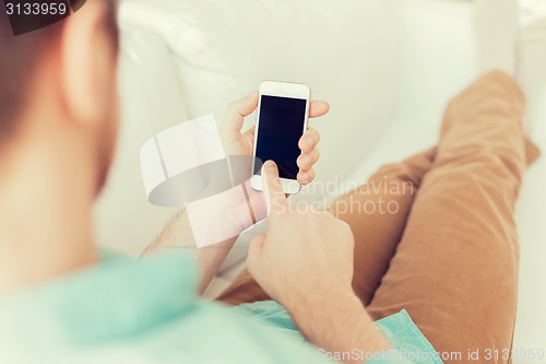 Image of close up of man sitting with smartphone at home