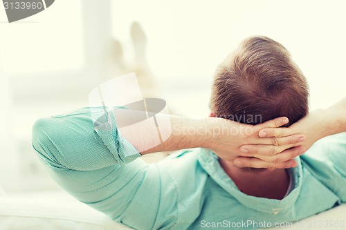 Image of man lying or sitting on sofa at home from back