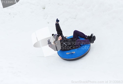 Image of happy young man sliding down on snow tube