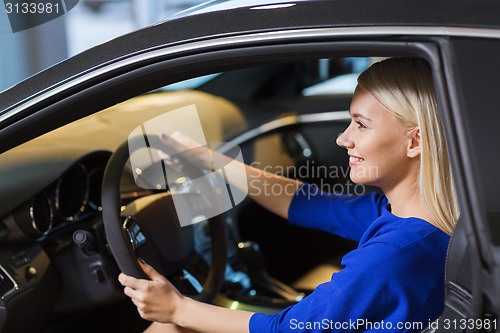 Image of happy woman inside car in auto show or salon